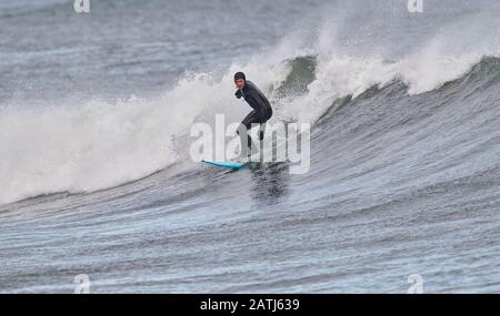 Surfisti invernali cavalcando onde Cherry Hill, Arties Cove, Nova Scotia, Canada. Foto Stock