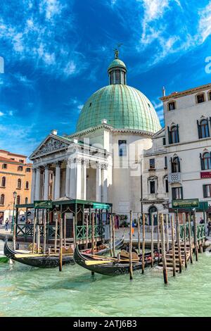 Gondole vuote ormeggiate su pali di ormeggio in legno presso una stazione della Gondola di fronte alla Chiesa di San Simeon piccolo sul Canal Grande di Venezia Foto Stock