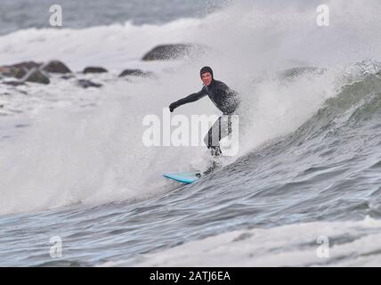 Surfisti invernali cavalcando onde Cherry Hill, Arties Cove, Nova Scotia, Canada. Foto Stock