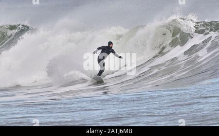 Surfisti invernali cavalcando onde Cherry Hill, Arties Cove, Nova Scotia, Canada. Foto Stock