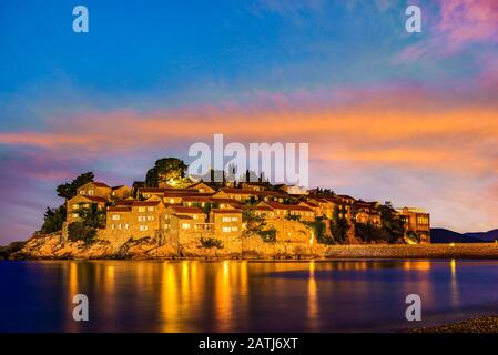 Cielo Fiery sull'isola di Sveti Stefan al tramonto, Montenegro Foto Stock