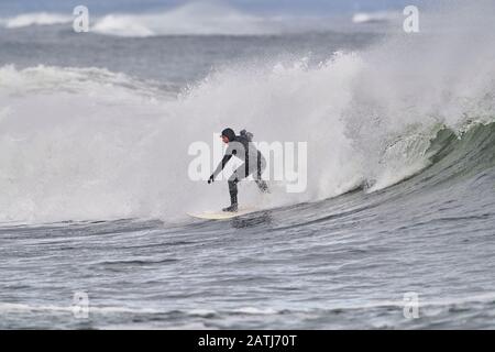 Surfisti invernali cavalcando onde Cherry Hill, Arties Cove, Nova Scotia, Canada. Foto Stock