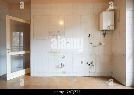 Vecchio muro di cucina vuoto con piastrelle bianche e sporche all'interno dell'appartamento Foto Stock