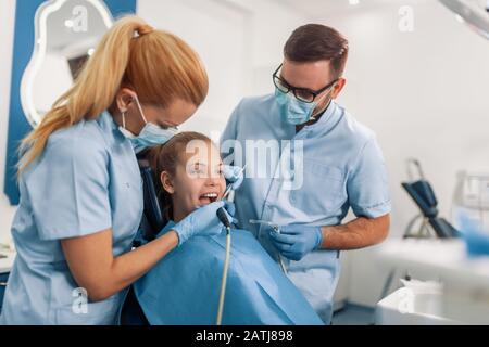 Il dentista dei bambini verifica i denti delle ragazze, mentre sedette sulla sedia dentale all'ufficio. Concetto di assistenza sanitaria. Foto Stock