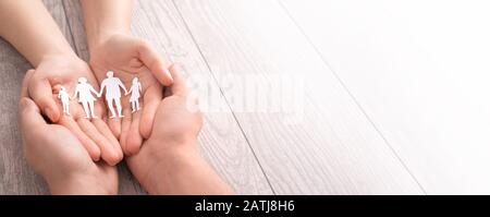 Mani con la silhouette di carta tagliata sul tavolo. Concetto di cura della famiglia. Foto Stock