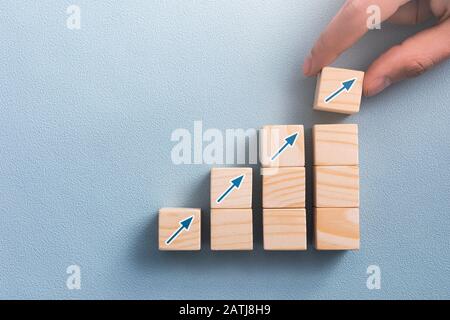 Mano che organizza blocco di legno con freccia su icona. Processo di successo per la crescita del concetto aziendale. Foto Stock