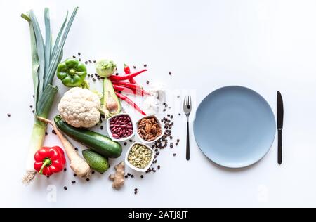 Vista dall'alto del gruppo di verdure fresche su sfondo bianco con piatto e posate . Spazio di copia Foto Stock