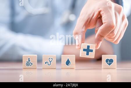 Mano disponendo il blocco di legno con healthcare medical icona. Assicurazione sanitaria - concetto. Foto Stock