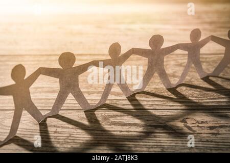 Team di persone della catena della carta. Catena umana con luce e ombra. Foto Stock