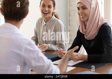 Gli impiegati multirazziali felici ridono discutere le idee durante la riunione Foto Stock