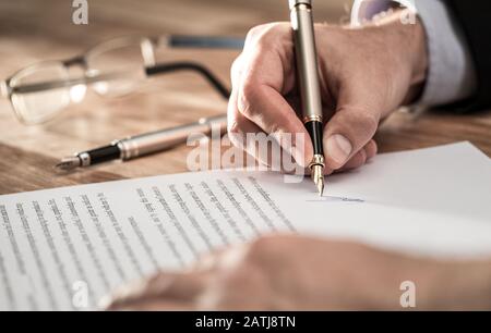 Uomo d'affari che firma il documento di contratto sulla scrivania dell'ufficio, facendo un affare. Foto Stock