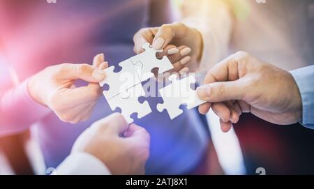 Un gruppo di uomini d'affari che assemblano puzzle jigsaw. Il concetto di cooperazione, lavoro di squadra, aiuto e sostegno alle imprese. Foto Stock