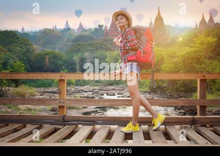 Giovane donna backpacker camminare sul ponte di legno al torrente Foto Stock