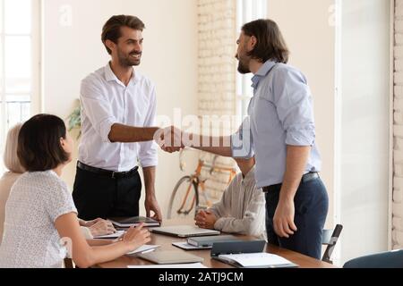 Uomo d'affari sorridente stretta di mano collega maschio al meeting di squadra Foto Stock