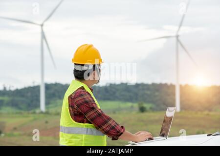 Ingegneria che lavora all'aperto nella fattoria di mulino a vento per energia Foto Stock