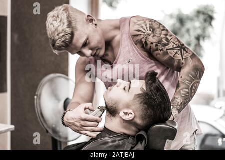 Barber regola la barba nel barbiere Foto Stock