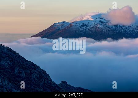 Antenne poste sulla cima di una montagna circondata da nuvole Foto Stock