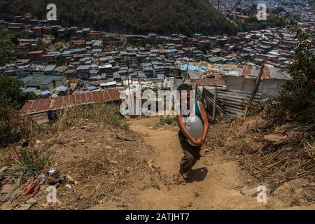 Un bambino porta una lattina d'acqua alla sua casa, poi passare diversi giorni senza acqua nelle comunità alte dei quartieri di Caracas. Foto Stock