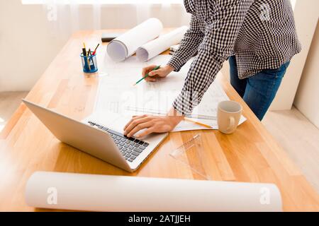 Uomo d'affari che guarda il piano disegnato mentre lavora sul portatile Foto Stock