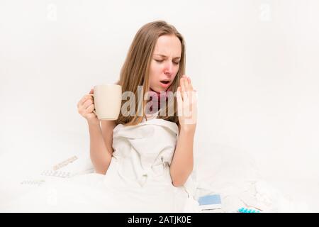 Donna malata che tiene una tazza di tè caldo e tendente Foto Stock