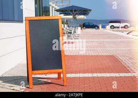 Nero menu bordo nero colore nero per testo, messaggio o pubblicità. Il mockup si trova vicino al ristorante sulla costa del mare. Giornata di sole. Foto Stock