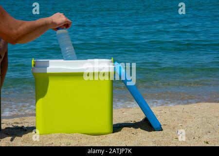 Un braccio umano sta prelevando una bottiglia d'acqua dal frigorifero portatile Foto Stock