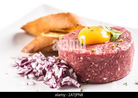 Tartare di manzo con tuorlo d'uovo erbe di cipolla rossa e bruschetta isolato su bianco Foto Stock