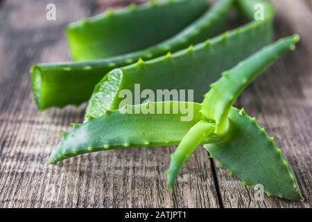 Foglie verdi di aloe primo piano su uno sfondo di legno. Aloe vera per il trattamento e la cura della pelle. Foto Stock