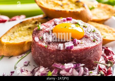 Tartare di manzo con tuorlo d'uovo cipolla rossa peperoncino peperoni erbe e bruschetta Foto Stock