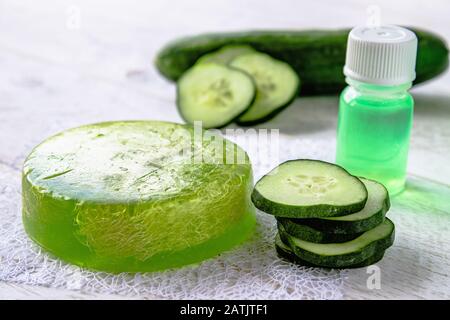 Estratto di cetriolo in una bottiglia con un pezzo di sapone e fette di cetriolo. Trattamenti Spa con sapone per cetrioli. Cura del corpo. Foto Stock