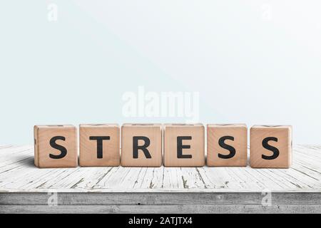 La parola stress su un segno fatto di blocchi di legno in una stanza luminosa su un tavolo Foto Stock