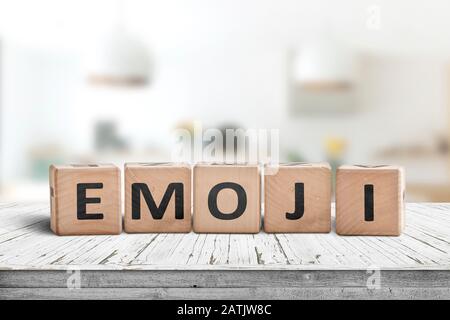 La parola gli Emoji su un cartello in legno in una sala luminosa su una scrivania bianca Foto Stock