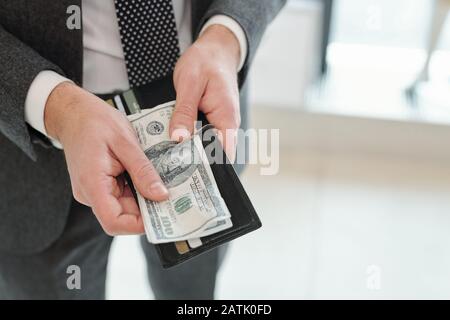 Primo piano di un uomo d'affari irriconoscibile in tuta ottenere soldi dal portafoglio con carte di credito e di sconto Foto Stock