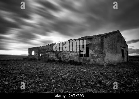 Un Suggestivo paesaggio cloudscape Di cieli Inquieti Sopra Un vecchio barn Crollato sulla campagna siciliana, Catania, Italia Foto Stock