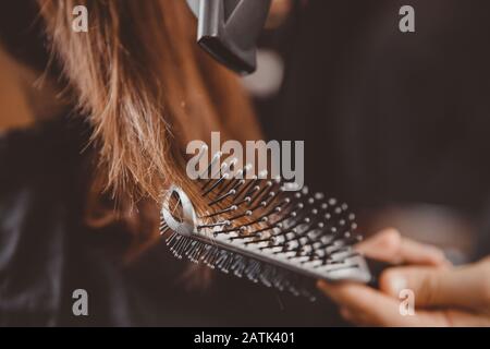 Barber rende l'acconciatura dei capelli all'uomo con asciugacapelli e pettine Foto Stock