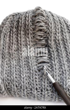 Tessitura a maglia grigio chiaro con difetto di fabbricazione isolato su bianco. Risoluzione dei problemi Foto Stock