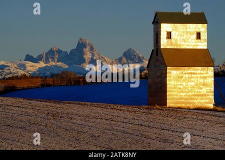 Antica costruzione di graine abbandonate con neve e Teton montagne sullo sfondo Foto Stock