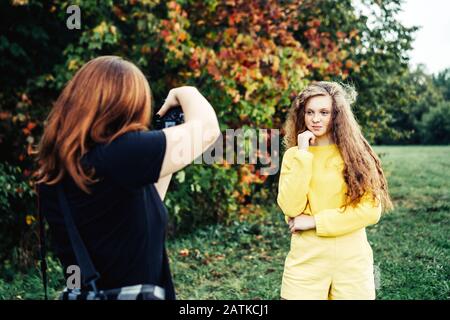 Fotografo donna che fotografa una ragazza adolescente con lunghi capelli ricci rossi Foto Stock