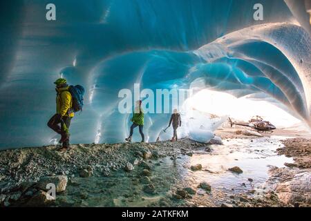 La guida avventura porta due clienti femminili in una grotta glaciale. Foto Stock