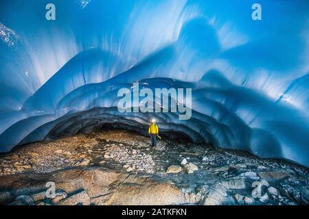 Alpinista in piedi nella grotta glaciale. Foto Stock