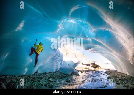 Uomo arrampicata su ghiaccio nella grotta di ghiaccio durante il tour avventura di lusso. Foto Stock
