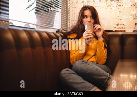 La ragazza teenage pensierosa bevendo il cioccolato milkshake in caffè Foto Stock