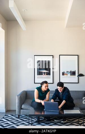 Colleghi di lavoro maschili e femminili che discutono di laptop a tavola in ufficio Foto Stock