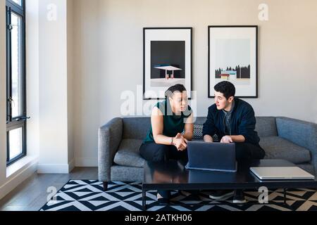 persone d'affari che discutono con un computer portatile seduto sul divano in ufficio Foto Stock