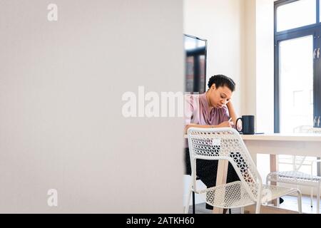 Giovane donna d'affari che scrive al tavolo in ufficio Foto Stock