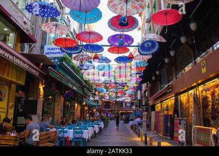 Istanbul, Turchia, 18 Settembre 2019. Ombrelloni colorati pendono dal cielo che copre una strada di bar, ristoranti, negozi nel quartiere Moda di Kadikoy Foto Stock