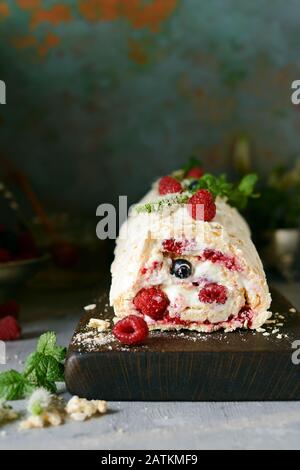 Meringa roll con una crema delicata e ariosa, menta e frutta ripieno da lamponi, ribes nero, mirtilli. Pavlova dolce d'estate Foto Stock