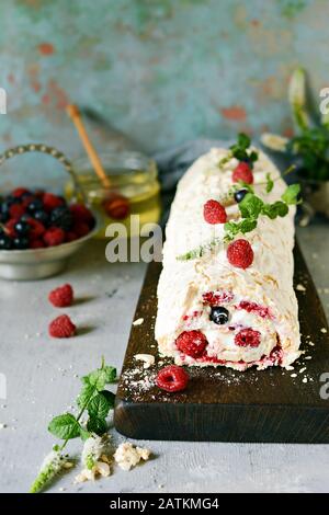 Meringa roll con una crema delicata e ariosa, menta e frutta ripieno da lamponi, ribes nero, mirtilli. Pavlova dolce d'estate Foto Stock