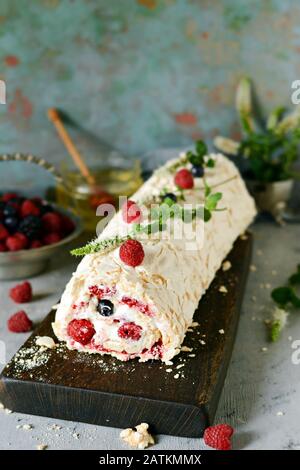 Meringa roll con una crema delicata e ariosa, menta e frutta ripieno da lamponi, ribes nero, mirtilli. Pavlova dolce d'estate Foto Stock