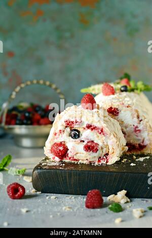 Meringa roll con una crema delicata e ariosa, menta e frutta ripieno da lamponi, ribes nero, mirtilli. Pavlova dolce d'estate Foto Stock